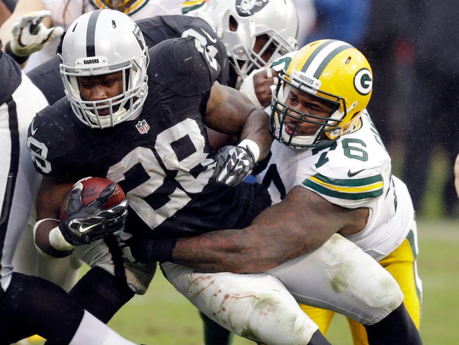 Oakland Raiders running back Latavius Murray (28) is tackled by Green Bay Packers defensive end Mike Daniels (76) on Sunday, Dec. 20, 2015, in Oakland, Calif. The Packers released Daniels on Wednesday as the team prepared to open training camp under new coach Matt LaFleur. [BEN MARGOT/THE ASSOCIATED PRESS]