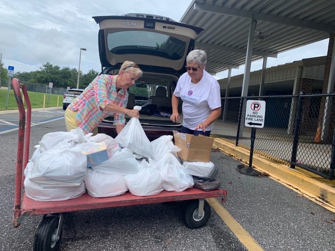 Nancy Hurlbert, left, the chairwoman of the Lake County Democratic Party, and Linda Kero, the party's office manager, load books onto a cart Thursday at Beverly Shores Elementary School. [Katie Sartoris/Daily Commercial]