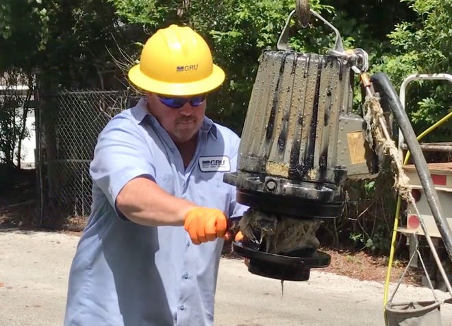 A Gainesville Regional Utility worker removes a mophead from a pump in Gainesville's wastewater system. [GRU via Vimeo]