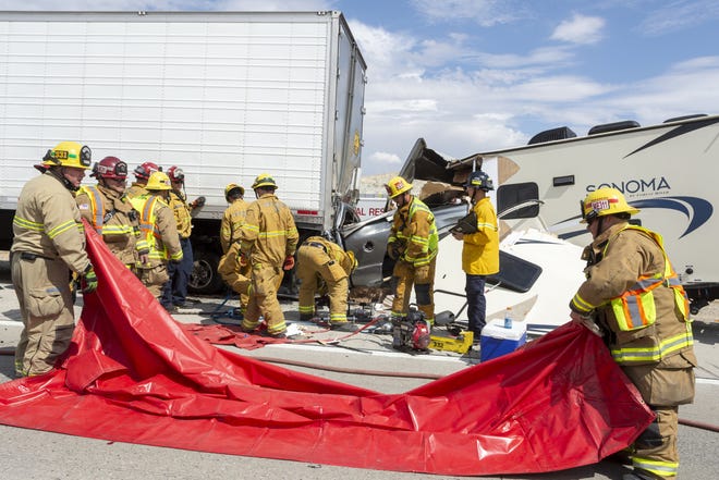 Apple Valley and Victorville firefighters prepare to remove a victim of a collision on Interstate 15 in Victorville on Thursday. A pickup truck towing an RV trailer collided with a semitrailer stopped on the shoulder near the Stoddard Wells Road exit. [James Quigg, Daily Press]