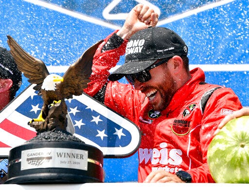 Ross Chastain celebrates in victory lane as teammates spray champagne after winning a NASCAR Truck Series auto race, Saturday, July 27, 2019, in Long Pond, Pa. (AP Photo/Derik Hamilton)