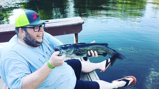 Outdoors editor Josh Rouse pulls out a 22 1/2-inch channel catfish from a dock at a private pond in Jefferson County. The mighty channel cat bit on the smallest of lures, a 1/32-ounce Fle-Fly lead-free feather jig on an ultralight rod and reel. [Brendan Handy/Special to The Capital-Journal]