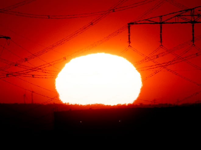 The sun rises near power lines in Frankfurt, Germany, Wednesday, July 24, 2019. A heatwave struck large parts of Europe. (AP Photo/Michael Probst)