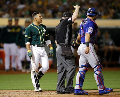 Oakland Athletics' Ramon Laureano, left, reacts after being hit by a pitch thrown by Texas Rangers' Rafael Montero in the eighth inning of a baseball game Saturday, July 27, 2019, in Oakland, Calif. At right is Rangers catcher Jeff Mathis. (AP Photo/Ben Margot)