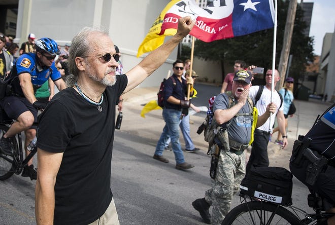 A man, left, participating in the November 2017 anti-fascist rally in Austin, holds his fist in the air while a counter-protester, right, shouts at him. NICK WAGNER / AMERICAN-STATESMAN