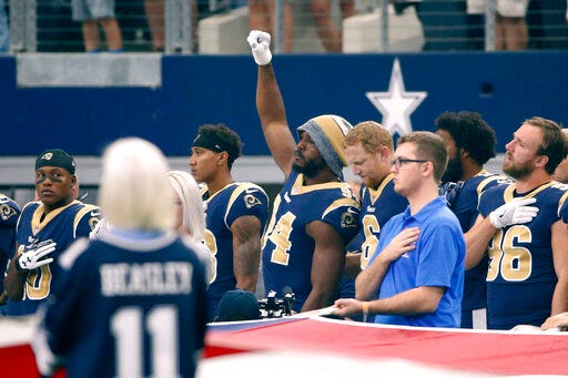 FILE - In this Oct. 1, 2017, file photo, then-Los Angeles Rams linebacker Robert Quinn (94) raises his fist during the playing of the national anthem before an NFL football game against the Dallas Cowboys, in Arlington, Texas. Dallas Cowboys defensive end Robert Quinn says the issue of protesting during the national anthem “might come up” before the season with owner Jerry Jones, who in the past has taken a hardline stance against displays by his players. Quinn joined the Cowboys in an offseason trade. (AP Photo/Ron Jenkins, File)