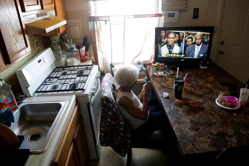 Carrie Newson watches television in the dining area inside her home at the Dutch Village apartments, Tuesday, July 30, 2019, in Baltimore. Newson has complained to management about mice and mold in her home but the issues have yet to be fixed. The apartment complex is owned by Jared Kushner, son-in-law of President Donald Trump. (AP Photo/Julio Cortez)
