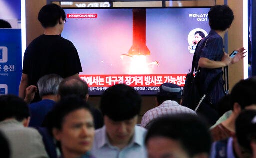People watch a TV showing a file image of North Korea's missile launch during a news program at the Seoul Railway Station in Seoul, South Korea, Wednesday, July 31, 2019. North Korea on Wednesday fired several unidentified projectiles off its east coast, South Korea's military said, less than a week after the North launched two short-range ballistic missiles into the sea in a defiance of U.N. resolutions. The signs read: "Possibility of long-distance multiple rocket launch system." (AP Photo/Ahn Young-joon)