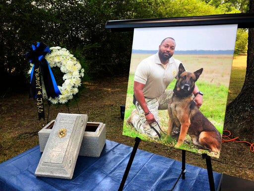A Tuesday, July 30, 2019 photo shows Alabama K-9 Jake, who died after coming into contact with a narcotic during a prison contraband search, was honored Tuesday with a 21-gun salute and commendation from Gov. Kay Ivey at the Staton Kennel Complex in Elmore. Pictured in the portrait is Jakes handler Sgt. Quinton Jones. (AP Photo/Blake Paterson)