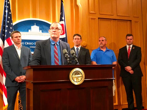 FILE - In a Tuesday, June 4, 2019 file photo, Roger Beedon discusses how sexual misconduct by now-deceased Ohio State team doctor Richard Strauss has affected his life, during a news conference with fellow Strauss accusers, from left, Brian Garrett, Dan Ritchie and Mike Flusche, and state Rep. Brett Hillyer, at the Statehouse in Columbus, Ohio. Men who say they were sexually abused by longtime Ohio State team doctor Richard Strauss are recounting how it changed their lives to make their case that the university owes them financial compensation. (AP Photo/Kantele Franko, File)