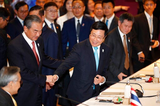 China's Foreign Minister Wang Yi, left, is greeted by Vietnam's Deputy Prime Minister and Foreign Minister Ph?m Binh Minh arrive at the ASEAN-China Foreign Ministers Meeting in Bangkok, Thailand, Wednesday, July 31, 2019. Southeast Asian foreign ministers opened their annual meeting Wednesday with a call from host Thailand for deeper integration amid rising global challenges and a pledge from China that differences will be "properly" resolved amid growing tensions in the South China Sea. (AP Photo/Gemunu Amarasinghe)