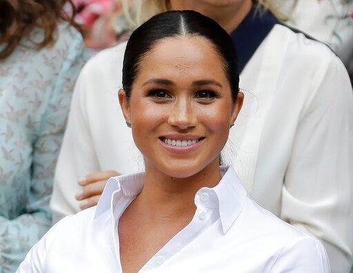 FILE - In this July 13, 2019 file photo, Kate, Meghan, Duchess of Sussex smiles while sitting in the Royal Box on Centre Court to watch the women's singles final match between Serena Williams, of the United States, and Romania's Simona Halep on at the Wimbledon Tennis Championships in London. Meghan has guest edited the September issue of British Vogue with the theme "Forces for Change." Royal officials say the issue coming out Aug. 2 features “change-makers united by their fearlessness in breaking barriers” and includes a conversation between Meghan and former U.S. first lady Michelle Obama. (AP Photo/Ben Curtis, File)
