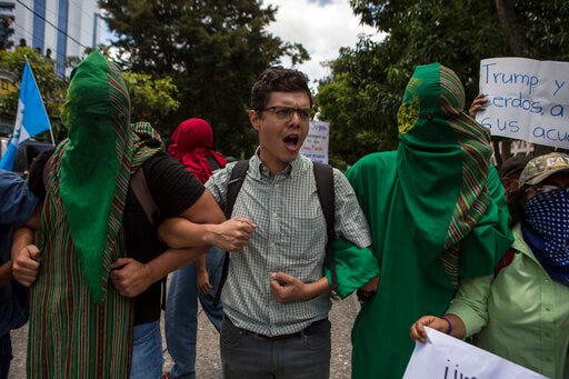 Agronomy students, some hooded, block a street outside the hotel where lawmakers were gathered and expected to vote on a deal that Guatemalan President Jimmy Morales' government signed with Washington forcing Salvadoran and Honduran migrants to request asylum in Guatemala instead of the United States, in Guatemala City, Wednesday, July 31, 2019. Critics of the deal point out that Guatemala has the same problems that are driving Hondurans and Salvadorans to flee their homes: violence, poverty, joblessness and a prolonged drought that has severely hurt farmers. (AP Photo/Oliver de Ros)