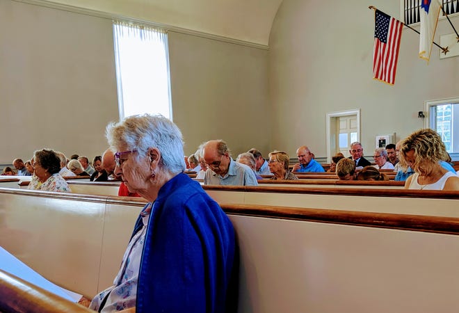 Members of First Parish Church read over the special meeting warrant Sunday, prior to voting unanimously to approve a proposed land settlement with the town of York. [Deborah McDermott/Seacoastonline]