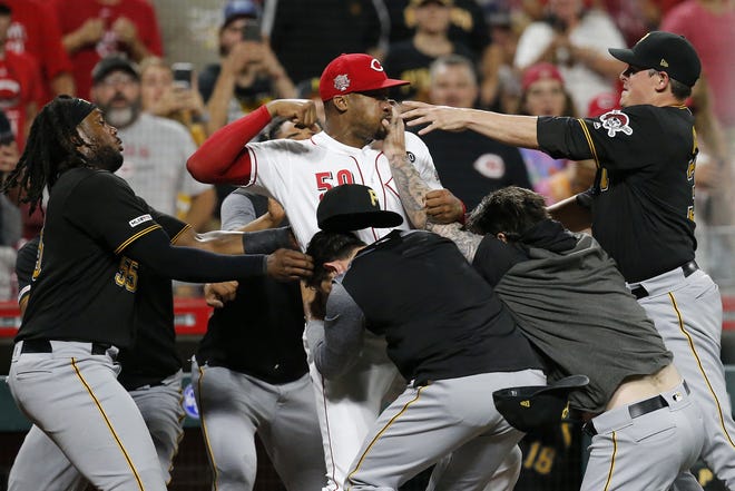 Cincinnati Reds relief pitcher Amir Garrett, center, looks to throw a punch as he is held back by a number of Pittsburgh Pirates players during a brawl in the ninth inning of a baseball game on Tuesday. The Pirates won 11-4. [SAM GREENE/THE CINCINNATI ENQUIRER VIA AP]
