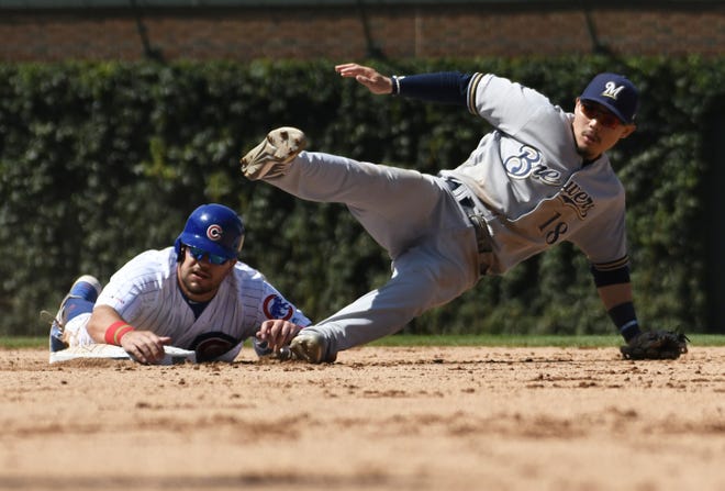 Milwaukee Brewers second baseman Keston Hiura, right, forces out Chicago Cubs outfielder Kyle Schwarber, left, at second base then throws to first base during the fifth inning Friday's game in Chicago. (AP Photo/David Banks)