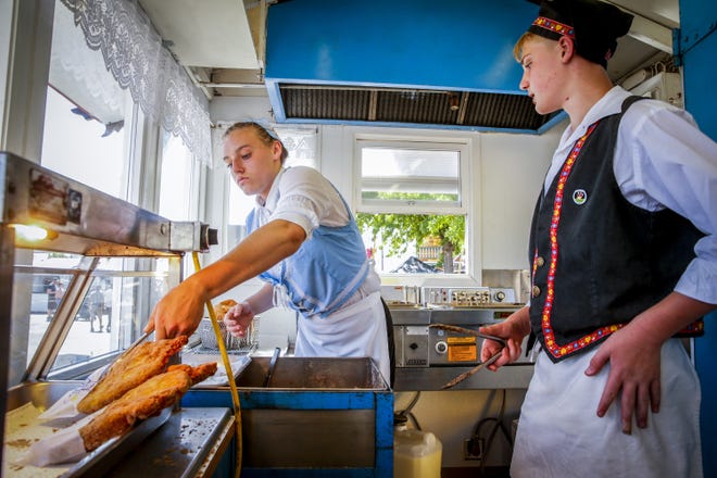 Jillian Liebersbach, 16, puts a freshly seasoned Fri-Jo, a Swedish pastry, under the warming lamps as Eli Mainenti, 13, watches on opening day at the 2019 Lane County Fair. [Dana Sparks/The Register-Guard] - registerguard.com