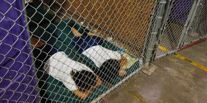 In this June 18, 2014, photo, two female detainees sleep in a holding cell, as the children are separated by age group and gender, at a US Customs and Border Protection center in Nogales, Arizona.
