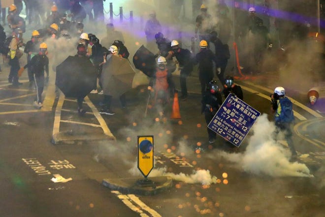 Protesters use umbrellas and roadsigns to shield from the tear gas fired by riot policemen during the anti-extradition bill protest at Causeway Bay in Hong Kong, on Sunday. The first of two planned protests in Hong Kong on Sunday kicked off from a public park just hours after police said they arrested more than 20 people for unlawful assembly and other offences during the previous night's demonstrations.