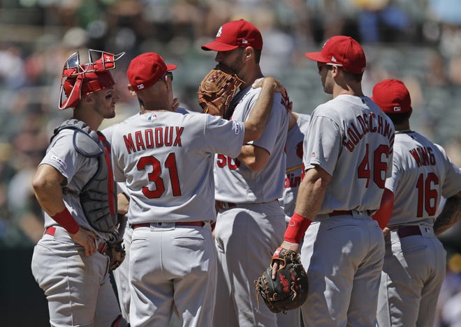 The St. Louis Cardinals' pitching coach Mike Maddux (31) speaks to pitcher Adam Wainwright, center, in the fifth inning against the Oakland Athletics, Sunday in Oakland, Calif. [BEN MARGOT/THE ASSOCIATED PRESS]