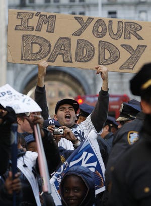 In this Nov. 6, 2009 photo, a fan holds a sign referring to Philadelphia Phillies pitcher Pedro Martinez, who was the losing pitcher in Game 6 of the World Series, during a ticker-tape parade along Broadway celebrating the New York Yankees 27th World Series championship, in New York. [AP PHOTO/KATHY WILLENS]