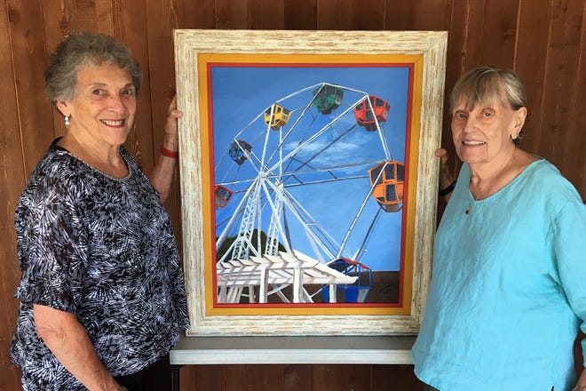 Patricia Hostetler Crolley (left) is shown with her painting of the Tuscora Park Ferris wheel, “The Sky’s the Limit.” At right is Renee Parson, director of the Forever Young Singers. People or businesses interested in buying the painting can make a bid at the Tuscarawas County Convention & Visitors Bureau through Aug. 15th. The choir will give a concert at 3:30 p.m. on Labor Day. Both the painting and the concert are fundraisers for Tuscora Park.