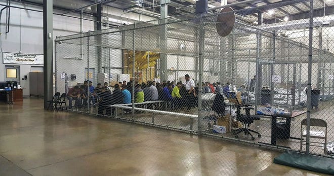 FILE PHOTO: In this June 17, 2018, photo provided by U.S. Customs and Border Protection, people who've been taken into custody related to cases of illegal entry into the United States, sit in one of the cages at a facility in McAllen, Texas.