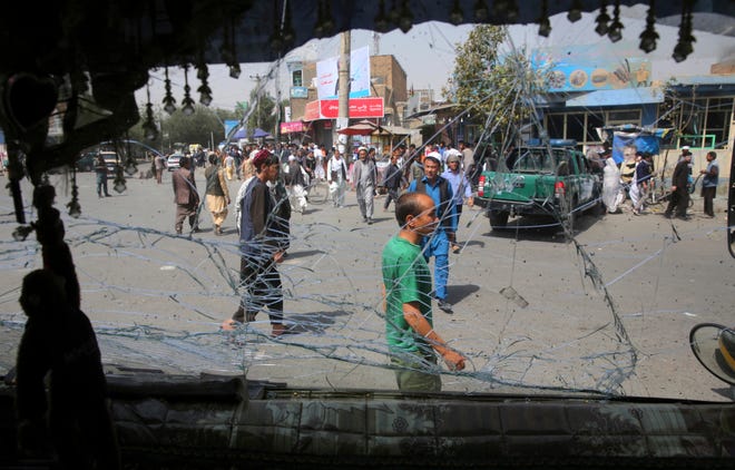 Afghans are seen through a shattered glass of a transport bus broken after an explosion Wednesday in Kabul, Afghanistan. A suicide car bomber targeted the police headquarters in a minority Shiite neighborhood in western Kabul on Wednesday, setting off a huge explosion that wounded dozens of people, Afghan officials said. The Taliban claimed responsibility for the bombing. [Rafiq Maqbool/The Associated Press]