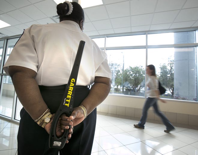A security officer stands at the metal detector with her metal-detecting wand as a visitor leaves the Marion County Judicial Center in Ocala. Gainesville officials are considering a number of security upgrades at City Hall, including adding metal detectors or security guards with wands. [Doug Engle/Ocala Star-Banner]