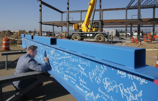 Jordan Pennell, a regional representative for Senator Sherrod Brown, signs his name to the final beam before a topping off ceremony for a gate expansion project at CAK Aug. 6, in Green. (GateHouse Media Ohio / Phil Masturzo, Beacon Journal/Ohio.com)