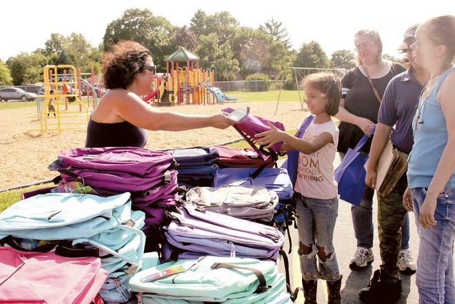 Evelia Fernandez, 10, of Sturgis, receives a backpack with supplies from Stacy Messner, a member of Sturgis Elks Lodge, at the club’s annual back-to-school giveaway. More than 300 backpacks were distributed at the event.