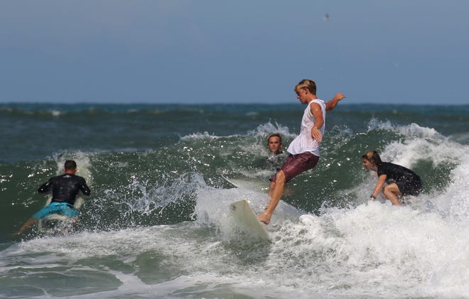 Surfers ride the waves south of the jetty where many of New Smyrna Beach's shark bites were reported. [News-Journal file/NIGEL COOK]