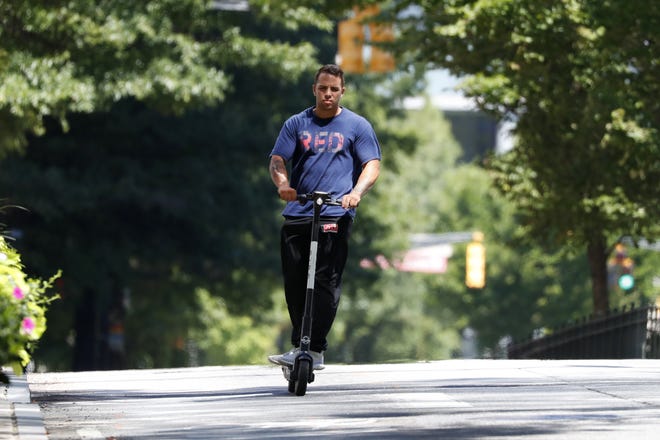 A man rides a electric scooter Thursday, Aug. 8, 2019, in Atlanta. Atlanta is banning electric scooters during nighttime hours during a deadly summer for riders. (AP Photo/John Bazemore)