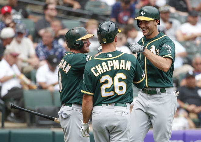 The Oakland Athletics' Matt Olson, right, is congratulated by Matt Chapman, center, and Robbie Grossman, left, after hitting a two-run home run off of Chicago White Sox's Lucas Giolito during the fourth inning Sunday in Chicago. [KAMIL KRZACZYNSKI/THE ASSOCIATED PRESS]