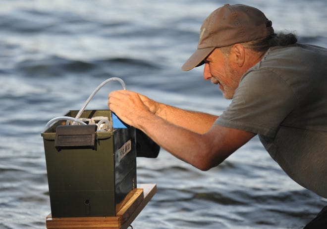 Charles "Chuck" Madansky, a volunteer with the Brewster Ponds Coalition, adjusts an aerosal testing device he sets out on Cliff Pond in Nickerson State Park to monitor for cyanobacteria. [Steve Heaslip/Cape Cod Times]