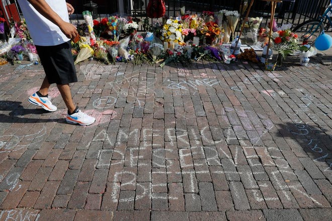 A pedestrian passes a makeshift memorial last week for the slain and injured victims of a mass shooting that occurred in the Oregon District in Dayton, Ohio, on Aug 4. Twenty-four-year-old Connor Betts opened fire in Dayton, killing several people including his sister, before officers fatally shot him.