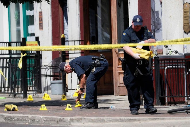 Authorities retrieve evidence markers at the scene of a mass shooting, Sunday, Aug. 4, 2019, in Dayton, Ohio.