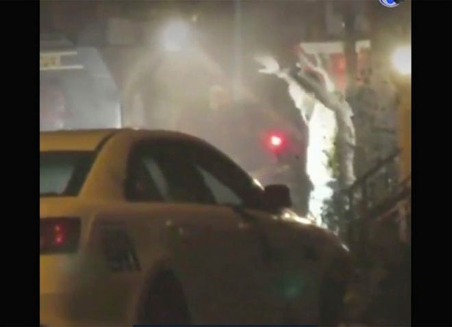 In this image from video taken by Bill Trenwith on Wednesday, Aug. 14, a man exits a building with hands up in Philadelphia, Pennsylvania. A gunman who opened fire on police Wednesday as they were serving a drug warrant in Philadelphia, wounding six officers and triggering a standoff that extended into the night, is in police custody, authorities said.