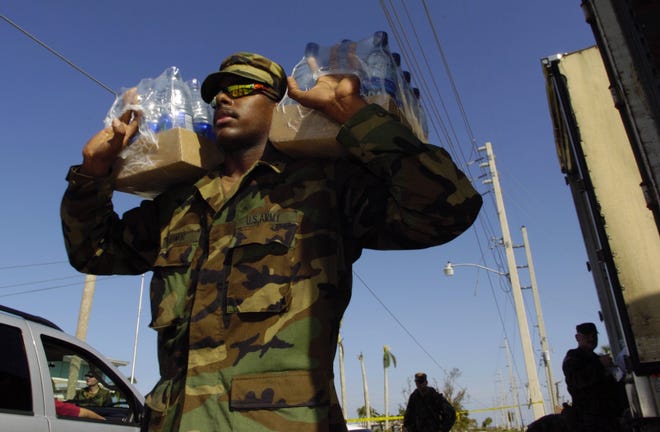 National Guard Pfc. Javier Zamor carries boxes of bottled water to the waiting cars of victims of Hurricane Charley on Aug. 15, 2004, in downtown Punta Gorda. The storm made landfall in Punta Gorda on Aug. 13, 2004. [Phil Diederich/Sarasota Herald-Tribune]