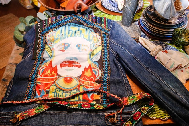 Heidi Ferguson, owner of the new thrift store Stitches and Rust, styles a jacket she plans to sew with a picture of Carlos Santana and straps from an old purse. These custom jean jackets sell fast. [CARLA TRIVINO/palmbeachpost.com]