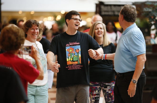 Randel Adkins, center, walks with Kip Tyner, right, and Nancy Snider, left, during the 14th Annual Walk to Remember inside University Mall Saturday, August 25, 2018. The walk honors all who are struggling with memory related diseases or who have passed away while suffering from such diseases. [Staff Photo/Gary Cosby Jr.]