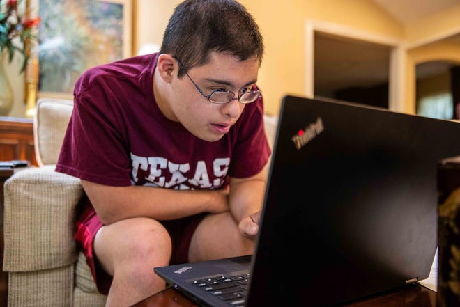 Miguel Gonzalez, 21, checks his laptop to play some music at his home in Austin last month. The 21-year-old with Down syndrome will participate in a four-year certificate program at Texas A&M University for students with intellectual and developmental disabilities, which is the first of its kind in Texas. [LOLA GOMEZ / AMERICAN-STATESMAN]