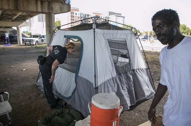 Amber Price, a community health paramedic and founding member of the city’s Homeless Outreach Street Team, checks on a homeless woman in a tent under Interstate 35 at Cesar Chavez Street on Tuesday. At right is Doug Huddleston, who also lives under the overpass. [JAY JANNER/AMERICAN-STATESMAN]