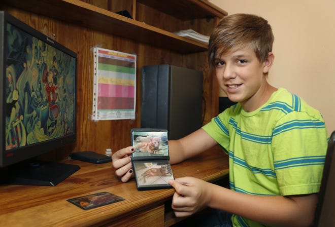 Nate Flo, 12, with photos of his emotional comfort therapy cat Percy at his home in Deltona, Thursday, August 8, 2019. [News-Journal/Nigel Cook]