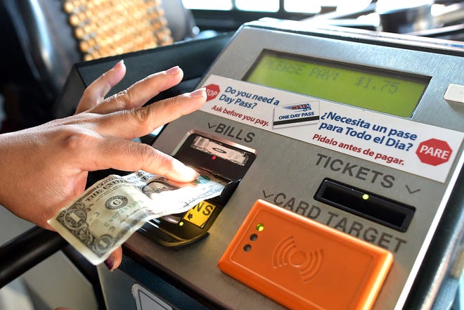 A woman inserts a dollar bill into a pay meter as she boards a bus at the WRTA hub at Union Station in Worcester. [T&G Staff/Steve Lanava]