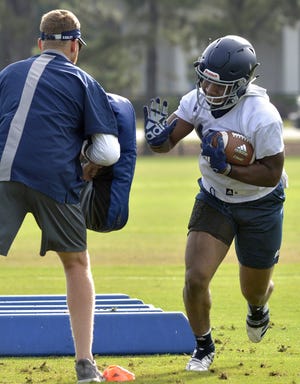 Running back J.D. King, right, punches the bag after running a drill during a recent practice. [STEVE BISSON/SAVANNAHNOW.COM]