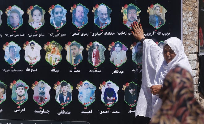 An Afghan woman cries as she touches a banner displaying photographs of victims of the Dubai City wedding hall bombing during a memorial service in Kabul, Afghanistan, Tuesday. The deadly bombing at a wedding in Afghanistan's capital late last Saturday that killed dozens of people was a stark reminder that the war-weary country faces daily threats not only from the long-established Taliban but also from a brutal local affiliate of the Islamic State group, which claimed responsibility for the attack. [RAFIQ MAGBOOL/ASSOCIATED PRESS]