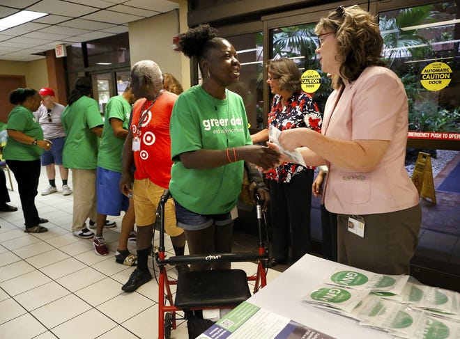 Stephanie Smith, left, smiles as she gets her package signifying she has completed her Green Dot training, as Tammy Carmichael, right, a program development manager with the Alachua County Health Department, hands her the package during a meeting at Oak Park apartments on last Thursday. [PHOTOS BY BRAD MCCLENNY/SPECIAL TO THE GUARDIAN]
