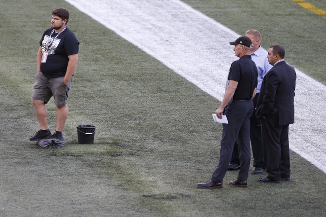 Officials assess the location where the CFL goal post holes were before an NFL preseason football game between the Oakland Raiders and the Green Bay Packers on Thursday, Aug. 22, 2019, in Winnipeg, Manitoba. Concerns about turf conditions prompted the NFL to shorten the field to 80 yards for the preseason game. [JOHN WOODS/THE CANADIAN PRESS VIA AP]