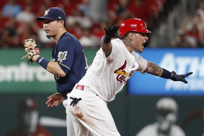 The Cardinals' Yadier Molina, right, celebrates after hitting an RBI double and avoiding the tag from Milwaukee second baseman Keston Hiura during the sixth inning of Wednesday night's game in St. Louis. [JEFF ROBERSON/THE ASSOCIATED PRESS]